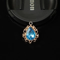 Détail macro du pendentif goutte vintage avec pierre bleue et bordure en dentelle dorée - Bleu lac
