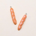 Close-up of resin baguette pendants with realistic bread texture and metal hanging loops - Baguette