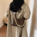 Brown quilted leather bucket bag with chunky gold chain strap worn by a female model - Brown