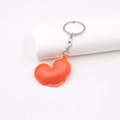 Detail of an orange heart-shaped PU leather keychain with a polished metal ring and chain - Orange