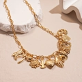 Detail der goldenen Halskette mit Anhängern wie Cowboystiefel, Herz und Kaktus - Gold