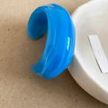 Detail van een brede acryl armband met blauw marmerpatroon op een wit dienblad - Blauw