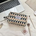 Detailed close-up of a floral corduroy cosmetic bag on a desk with a laptop and makeup - Little Blue Flower