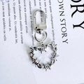 Punk style silver heart keychain with thorn texture and secure lobster clasp hanging on magazine - White Barbed Wire Heart