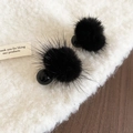 Close-up of black fuzzy pompom earrings with glossy beads on a soft beige fabric - Silver Needle Studs / Black