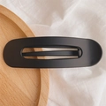 Detail view of large matte black duckbill hair clip with hollow oval design on fabric - Matte Black