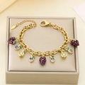 Detailed shot of a gold charm bracelet with purple strawberry and orange slice pendants - Purple Strawberry Orange Style (KB203067-Z)