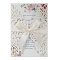 Macro detail of ivory laser-cut wedding invitation with glitter finish and satin bow - Ivory