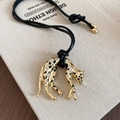 Makro-Detail des goldenen Leoparden-Anhängers mit schwarzen Punkten und funkelnden Strass - Gold-Schwarz