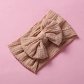 Close-up of soft knit baby headband with cable texture and large pink bow decoration - Khaki