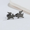 Macro shot of unique matte black winged pig stud earrings made of stainless steel - Flying Pig / Black