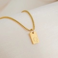 Macro shot of 18K gold plated square pendant with engraved letter Q on a box chain - Letter Q