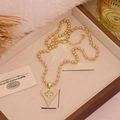Vergulde hartketting met een met zirkoon bezette klaverhanger op een luxe display - Kruis Hart Hanger