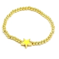 Detail eines goldenen Perlenarmbands mit einem leuchtend gelben Sternanhänger auf Weiß - Gelb