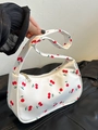 Close-up of cherry pattern on white nylon fabric with golden zipper detail on handbag - Cherry
