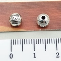 Silver Tibetan beads with geometric patterns and central hole on a measuring ruler - Geometric Texture Spacer Bead