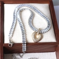 Elegant gold heart pendant necklace with square-cut zircons on a white jewelry display - Silver