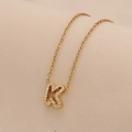 Detailed view of a gold letter K pendant necklace with sparkling crystal inlay - Letter K