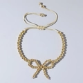 Handmade adjustable beaded bracelet with a golden bow charm and cream woven cord - Pure Gold Bead Bow (JS-B24022901B)