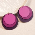 Detail of layered purple geometric wooden hoop earrings on a textured white surface - Purple Gradient