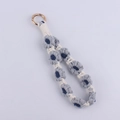 Close-up of handmade crochet daisy flower wrist strap with polished golden metal ring - Gray