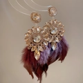 Dettaglio macro di orecchini con nappe di piume rosso vino e cristalli stile vintage - Marrone