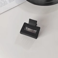 Gros plan d'une pince à cheveux rectangulaire noire mate sur une surface blanche - Pince à Cheveux Carrée Noire
