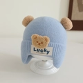 Nahaufnahme der Strickmütze für Babys mit zwei Pompons und Bären-Aufnäher in Hellblau - 1-3 Jahre / Blau