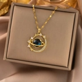 Detail shot of golden planet necklace with blue orb and crescent moon frame on silk box - Gold Planet