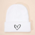 Close-up of white knit beanie texture and black embroidered heart on the folded cuff - White