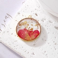 Detail of round resin pendant with red dried flowers and gold foil in a bronze frame - January Carnation With Gold Foil
