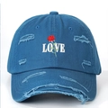 Detailopname van rozenborduursel en LOVE-tekst op een blauwe distressed baseballpet - Eén maat / Blauw