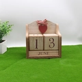 Calendrier perpétuel en bois avec cœur rouge et ruban posé sur gazon vert - Cœur Rouge Rétro