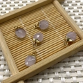 Five faceted pink quartz teardrop pendants with gold plated caps on a bamboo tray - Rose Quartz