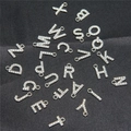 Nahaufnahme von silbernen Alphabet-Anhängern mit Strass auf schwarzem Stoffgrund - Strass-Alphabet-Set (DY147) / 26er Set / Stil 51 Weiß K