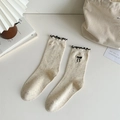 Creamy white crew socks with colorful speckles, black ruffle edges, and a cute bow detail - Black