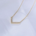Detail of V-shaped gold necklace with sparkling zircon pavé on white silk background - 925 Silver / Gold