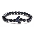 Vista macro del bracciale di perline in pietra blu con ciondolo a forma di uccello - Pietra Stellaria Blu Farfalla (Corda Elastica)