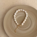 Detailed view of white baroque pearl bracelet with adjustable gold clasp on beige plate - Baroque Pearl Bracelet