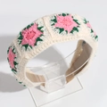 Close-up of hand-knitted beige headband featuring pink and green floral embroidery details - Pink & White