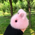 Plush pink bunny keychain with soft faux fur and pink ears shown in a forest background - Pink Strap Style