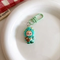 Macro shot of green cartoon figurine keychain with bear charm on a white ceramic plate - Dinosaur Style