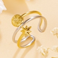 Dreilagiger Edelstahlring mit goldenen Sonnen- und Sternanhängern auf warmem Grund - Gold & Silber