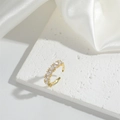 Adjustable gold open ring featuring a clear rectangular zircon on white silk background - Triangle Zirconia