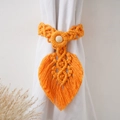 Close-up of orange leaf-shaped woven curtain tieback with a wooden bead on white fabric - Style A Woven Pattern / Gold Yellow