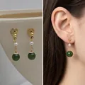 Detail of vintage French clip earrings with golden spiral disc, pearl and green jade bead - Green Gemstone Pearl Clip-on
