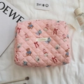 Nahaufnahme der rosa gesteppten Kosmetiktasche mit Bärenmuster und Stoffetikett - Rosa Puppenmuster