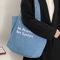 Bolso tote de mezclilla azul con estampado blanco sobre una chaqueta negra elegante - Azul claro