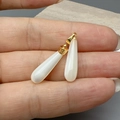 Colgantes de concha blanca en forma de gota con aros dorados mostrados sobre la mano - Blanco