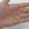 Collana con pendente a cuore dorato con catena a serpente tenuta in mano - Cuore storto